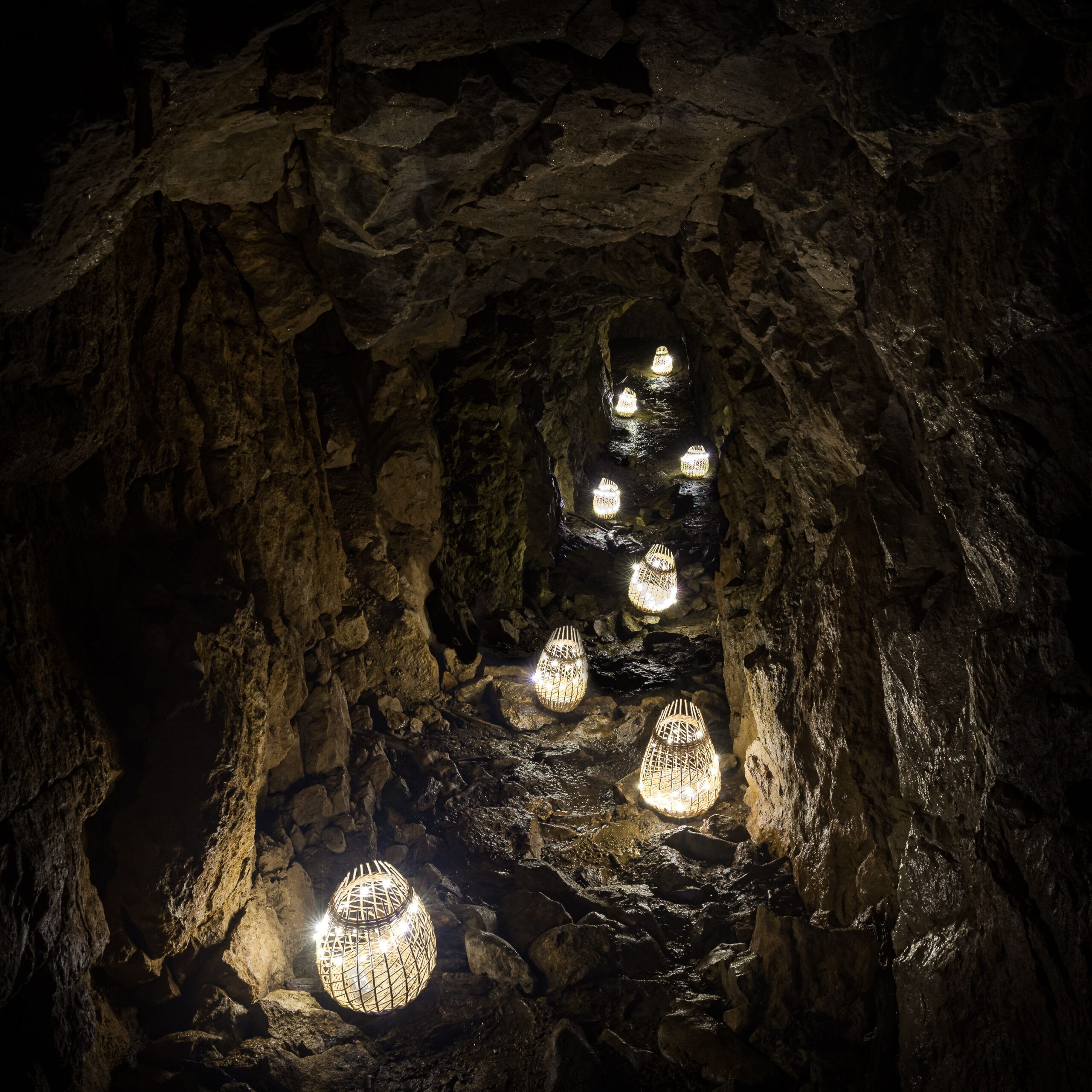Des paniers lumineux éclairent le cheminement d'une grotte.